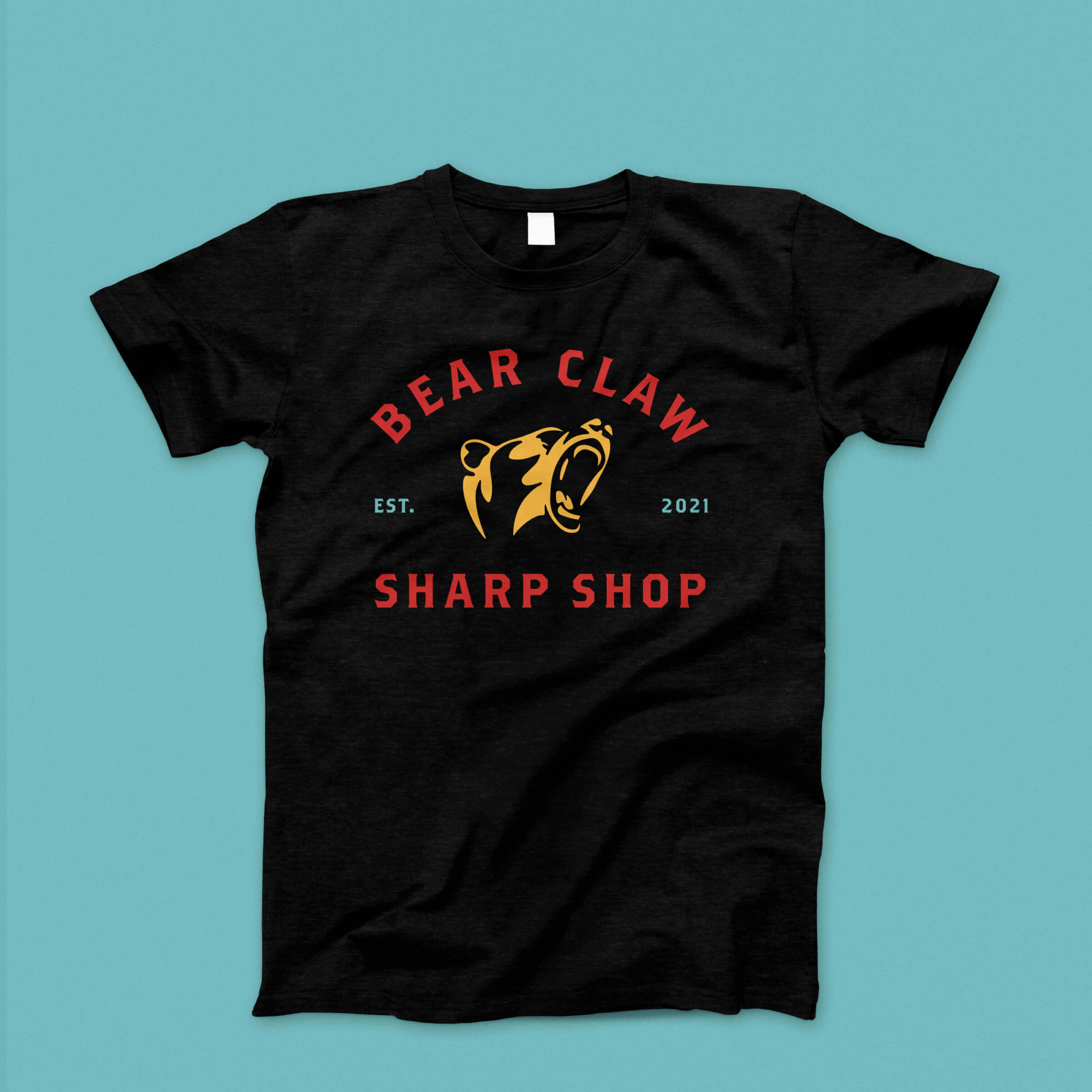 A black t-shirt on a teal background with the Bear Claw Sharp Shop logo.