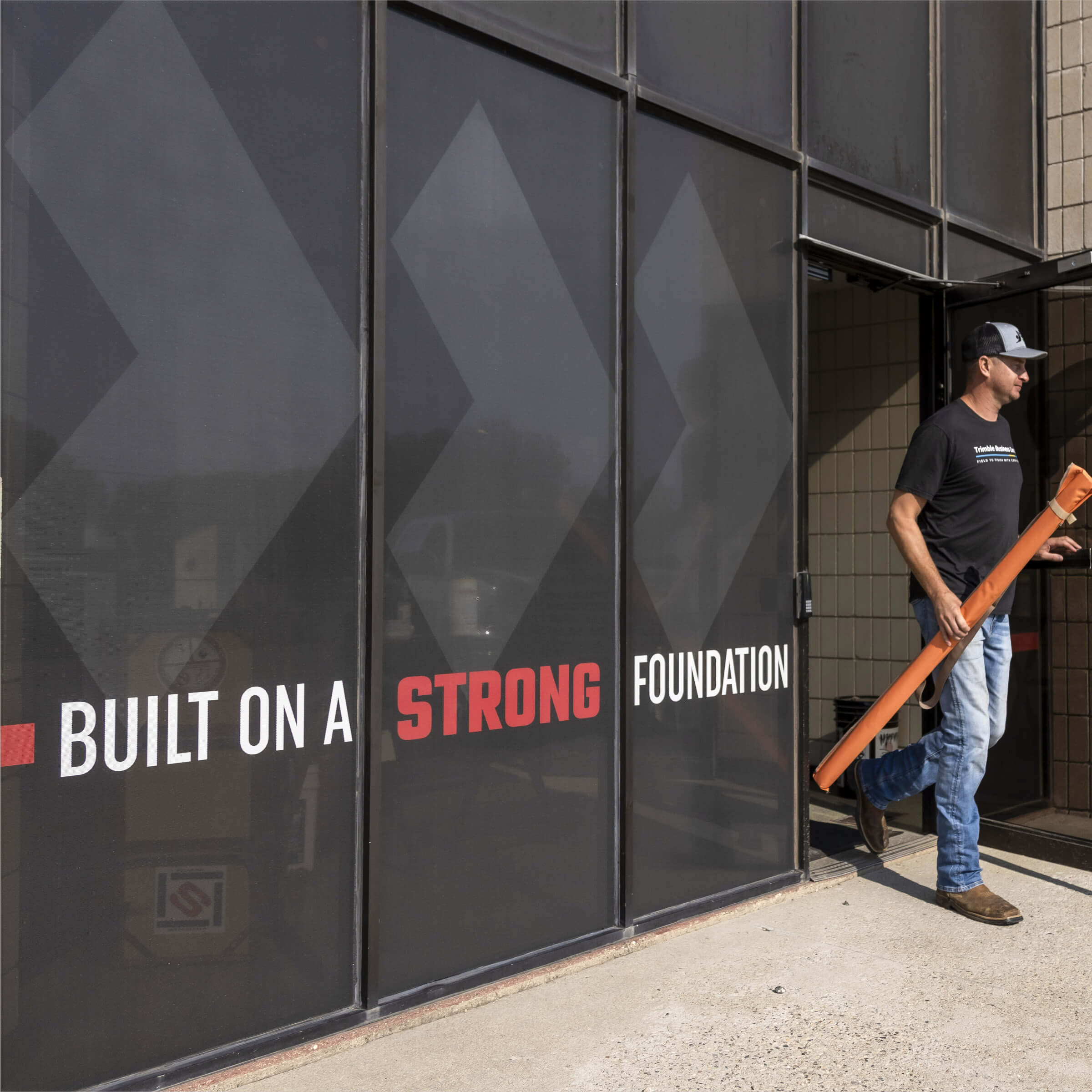 An employee walking out the front door of an office building. Built on a strong foundation window graphic.
