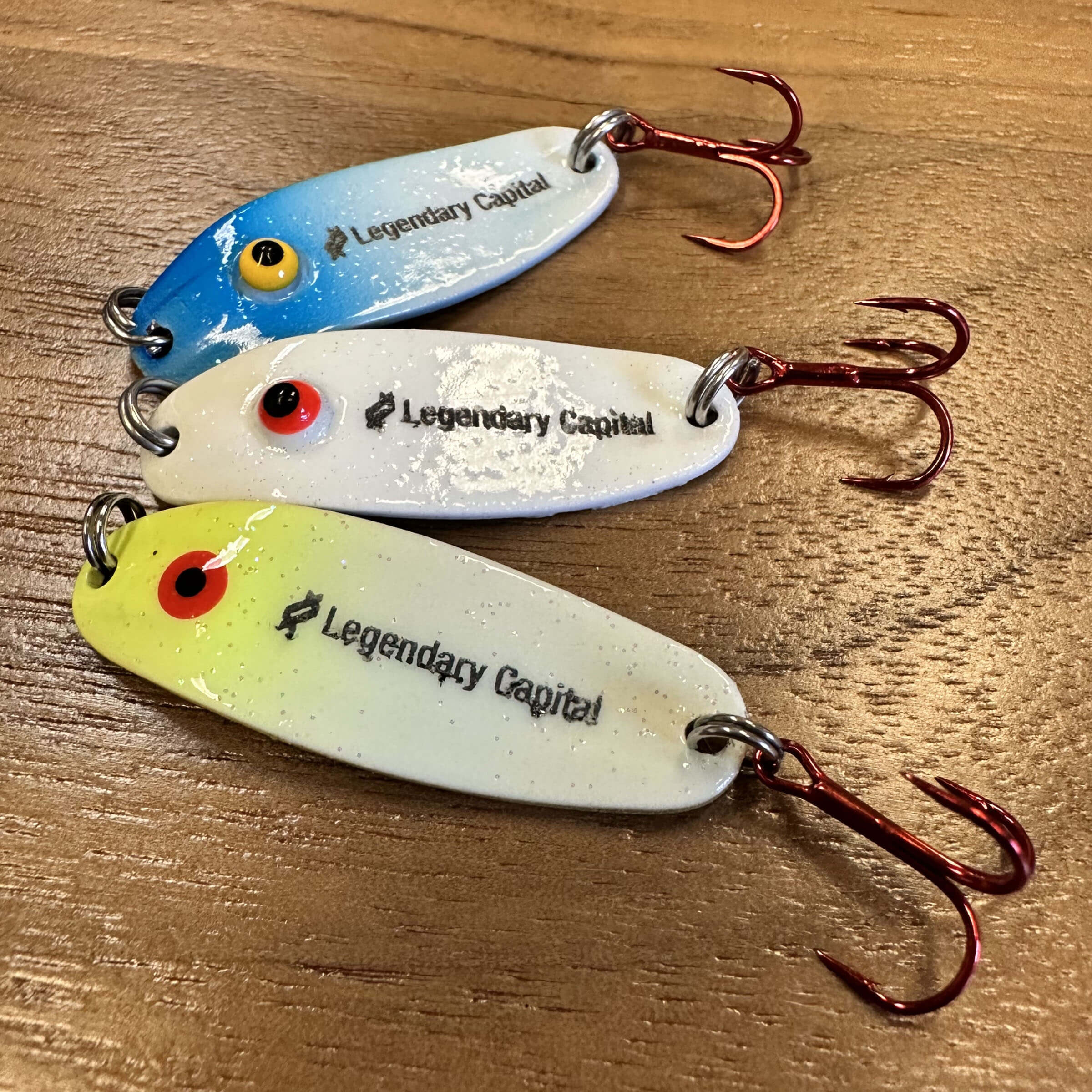 Three fishing lures with the company logo engraved.