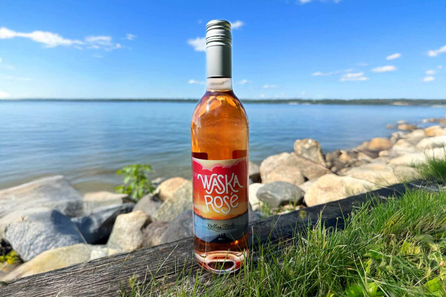Rose wine bottle in front of lake